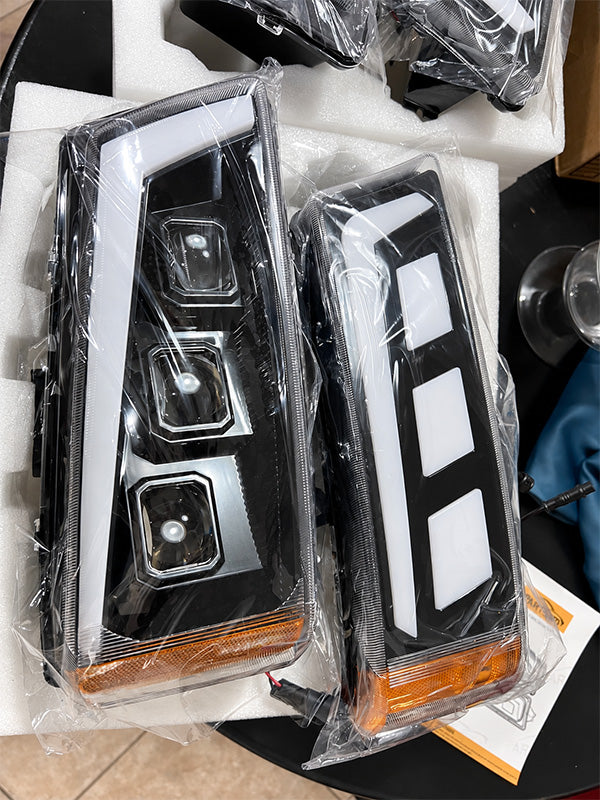 A pair of custom black LED headlight assemblies with white and amber accents, still in their clear plastic wrapping, displayed on white foam packaging.